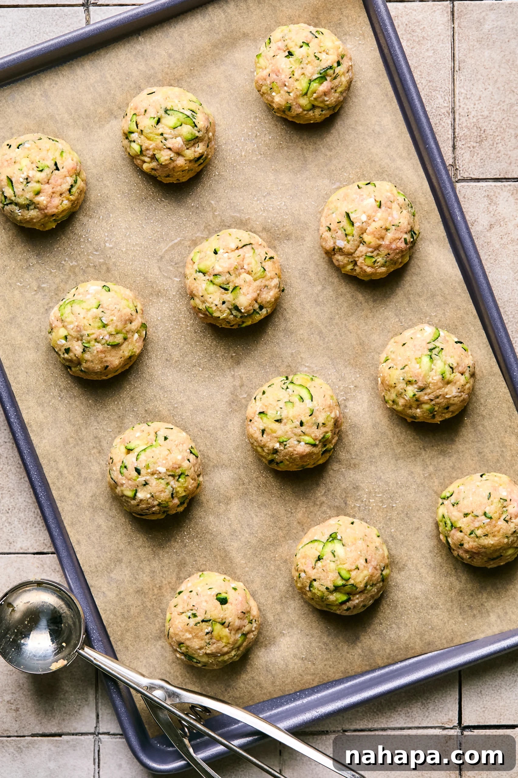 Zesty Gluten-Free Turkey Feta Bites 7 Uncooked turkey feta meatballs neatly arranged on a parchment-lined baking sheet, ready for the oven.