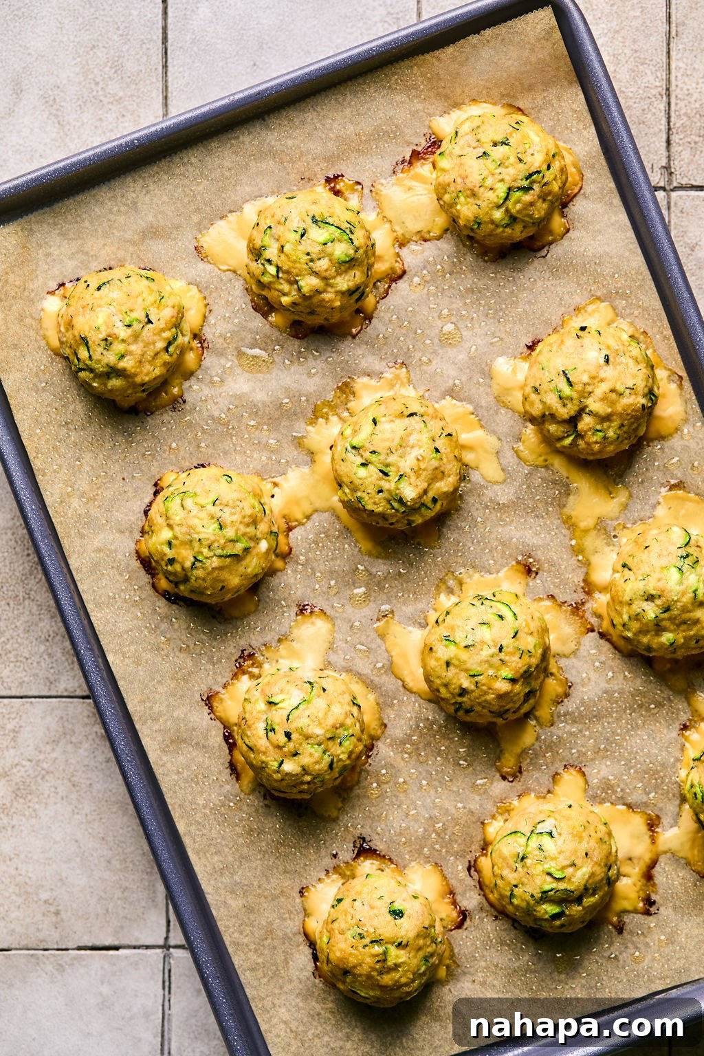 Zesty Gluten-Free Turkey Feta Bites 9 Cooked turkey feta meatballs, golden brown and perfectly baked, resting on a parchment-lined baking sheet.