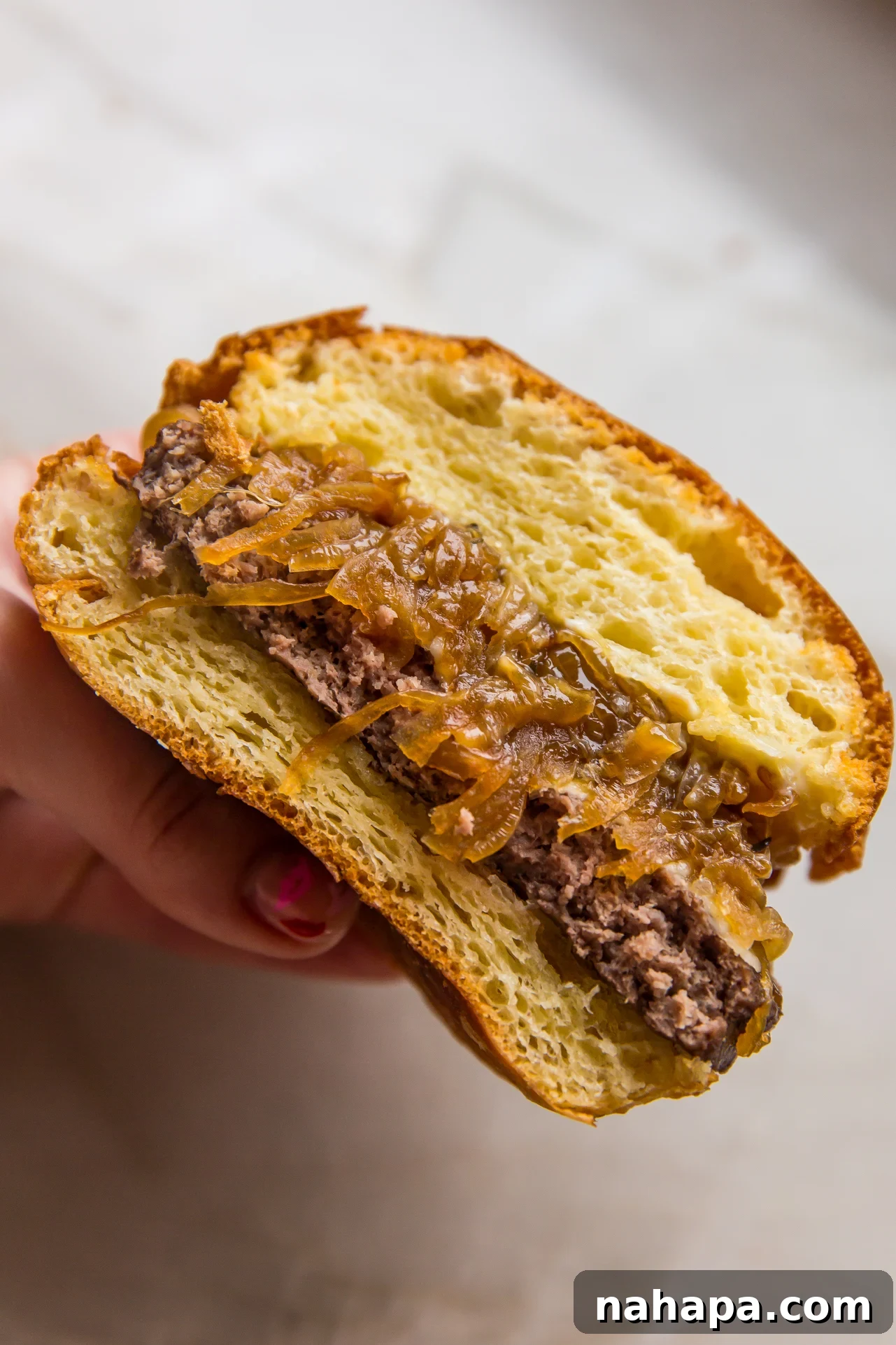 French onion burger sliced in half and being held.