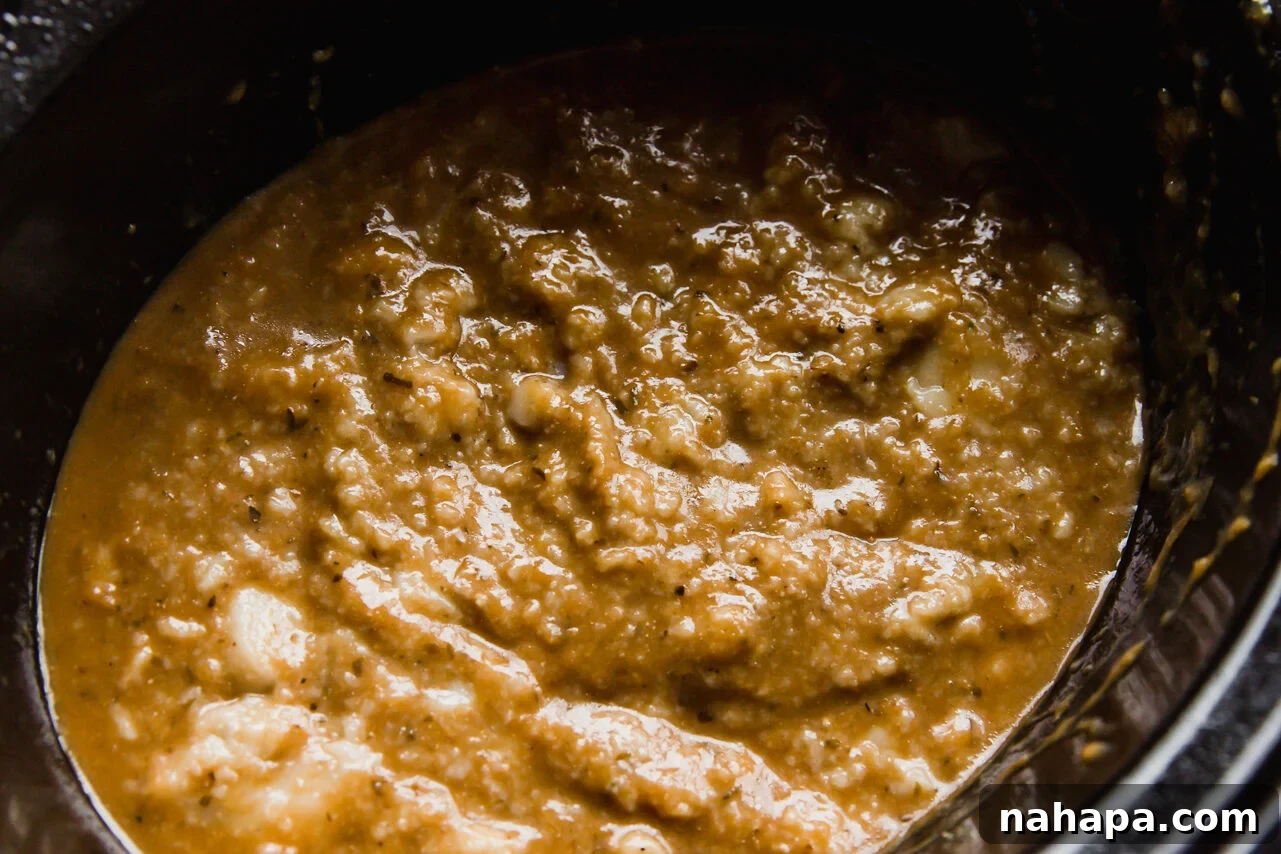 Velvety Slow Cooker Chicken Pasta 4 Raw chicken breast seasoned and covered with a blend of Daylight Veggie Pasta Sauce and dairy-free alfredo sauce in a slow cooker, ready for cooking.