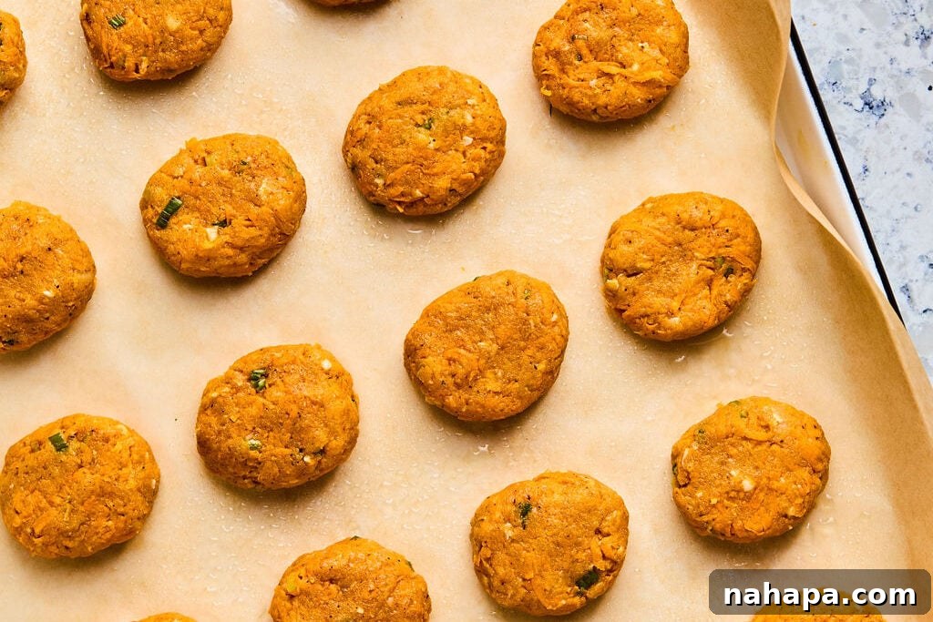 Uncooked sweet potato chicken poppers on a sheet pan. 