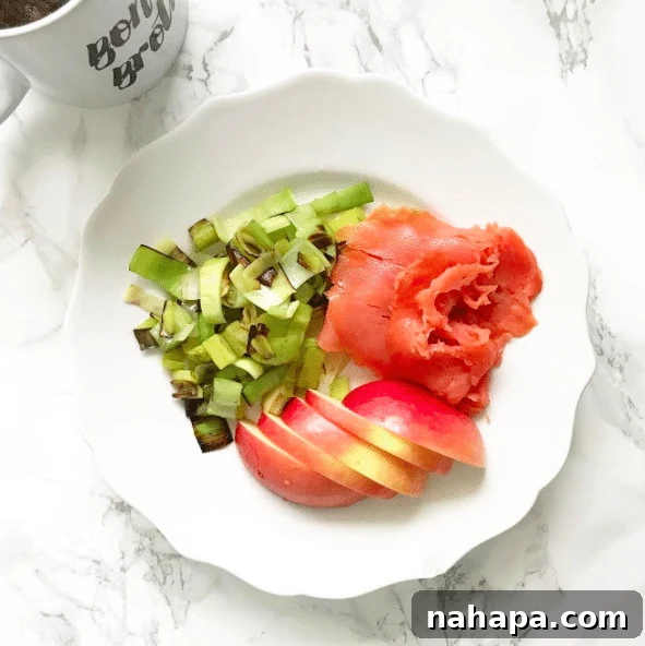 A plate with apple slices, smoked salmon, and fresh greens.