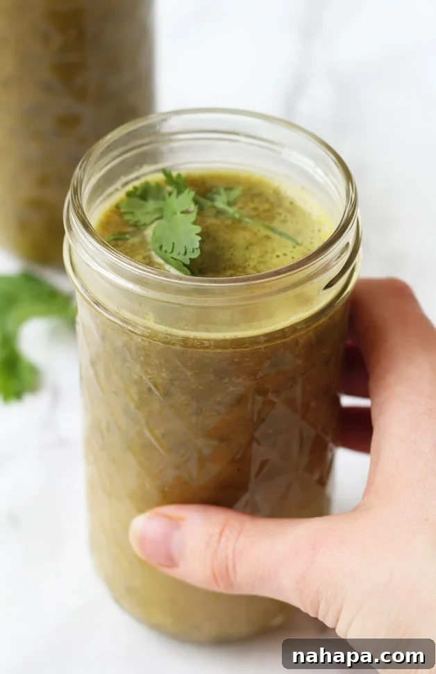 Green Bone Broth Elixir 2 A glass mug of bone broth green drink being held in a hand.