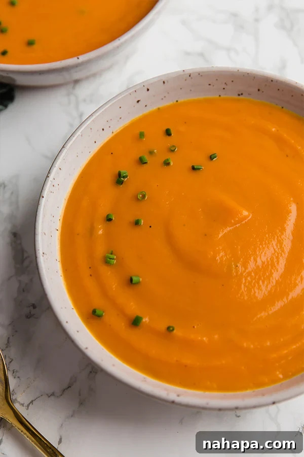 Warm and inviting bowl of Carrot Leek Turmeric Soup garnished with fresh chives, ready to be enjoyed.
