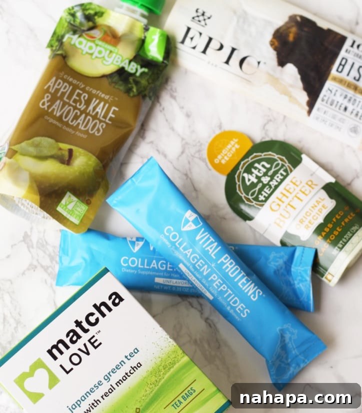 Your Paleo & AIP Travel Food Guide & Checklist 6 Matcha, two packets of collagen, a travel sized container of ghee, and an epic bar out on a marble background.