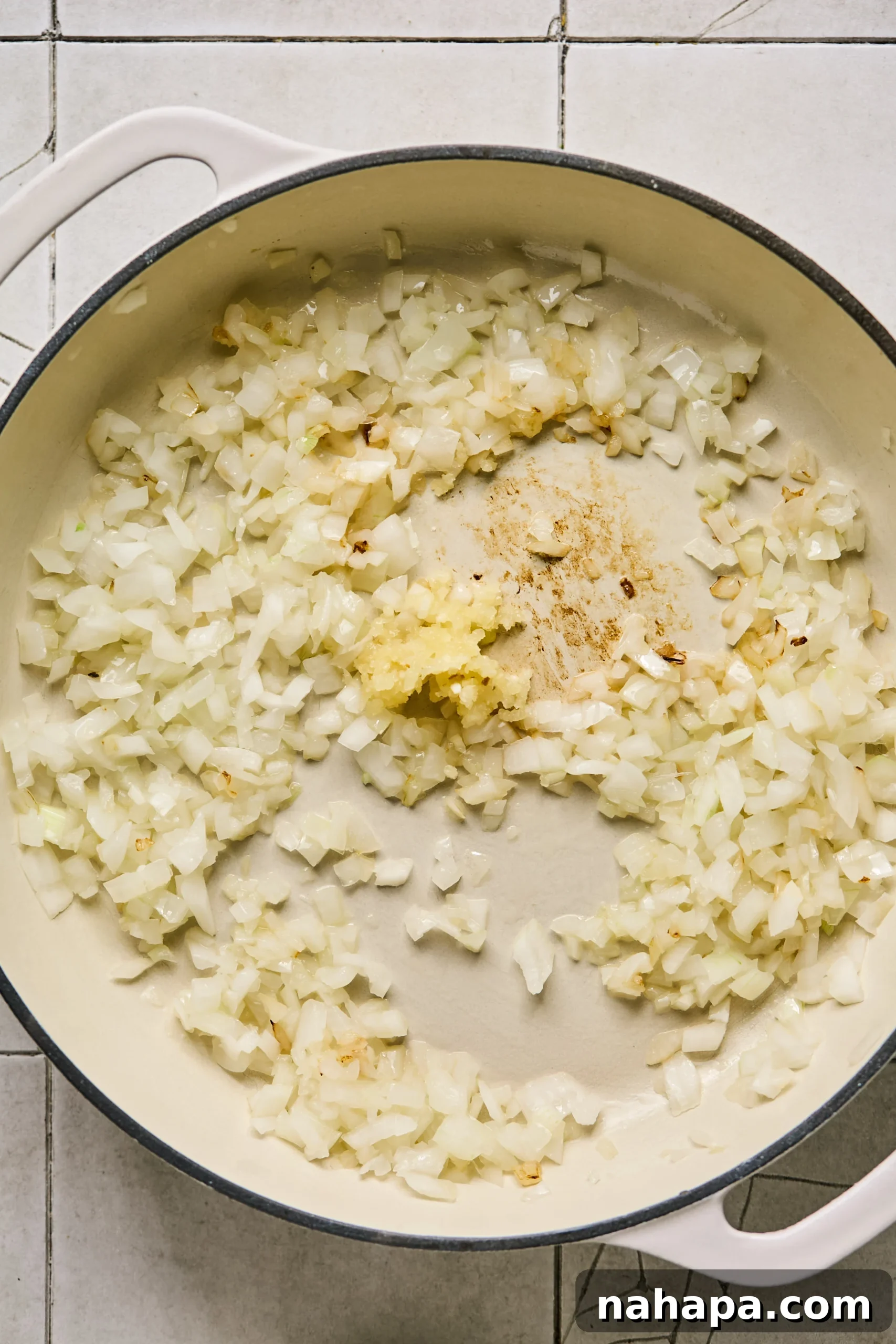 Diced yellow onion and minced garlic sautéing in a large pan until softened and fragrant.