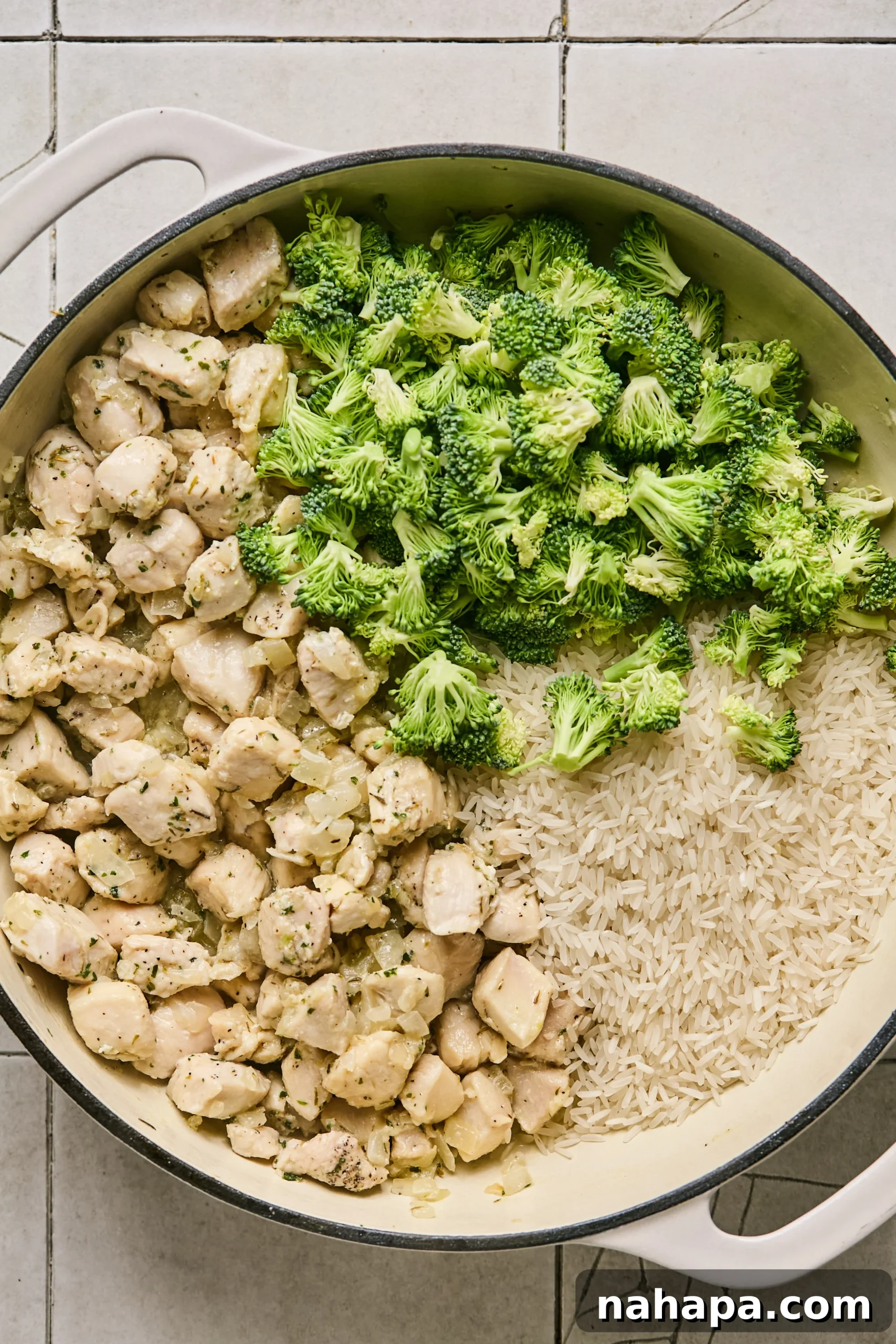 Rinsed jasmine rice and chopped broccoli florets added to one side of the pan with chicken and aromatics.