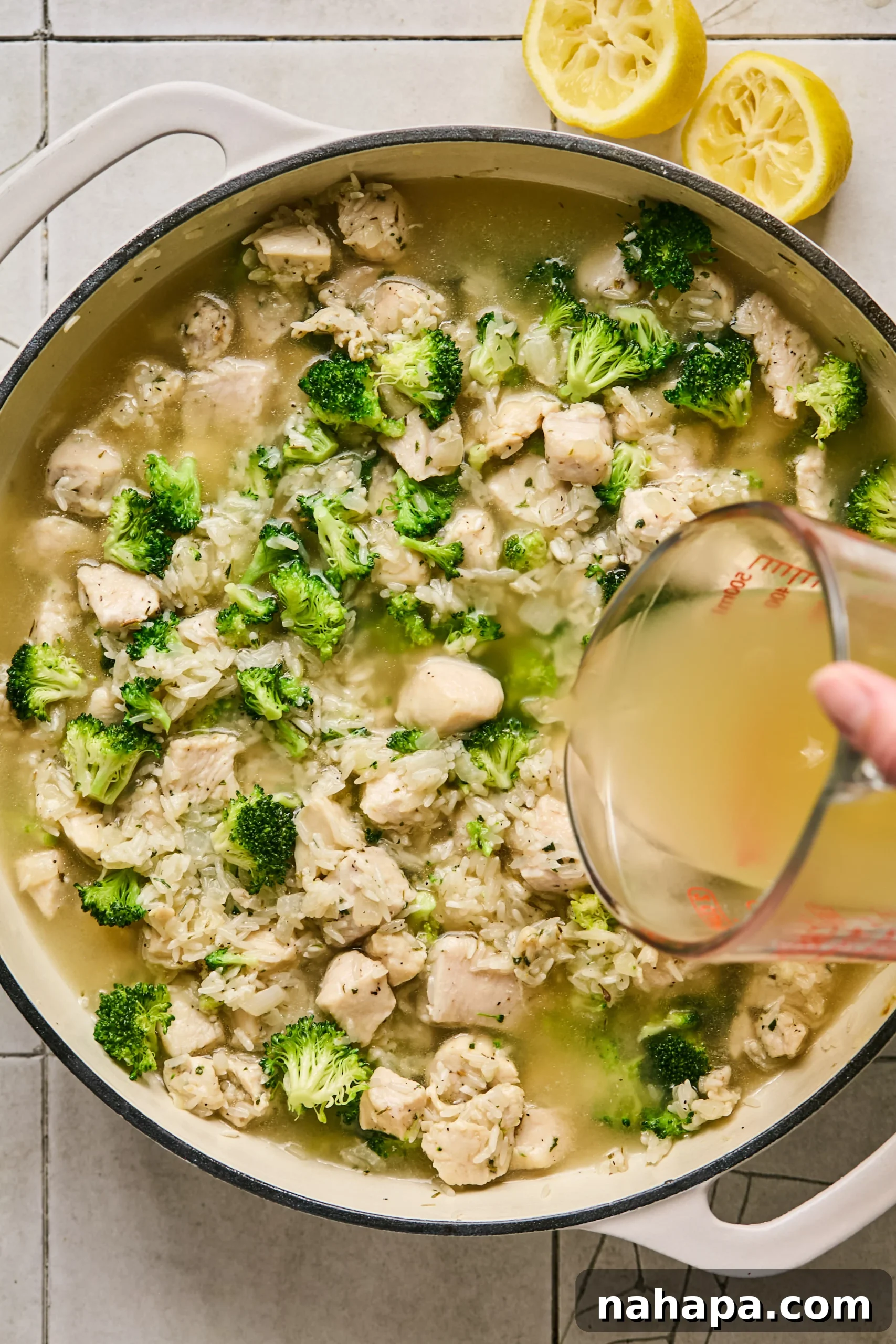 Chicken broth and lemon juice poured into the pan with the chicken, broccoli, and rice mixture.