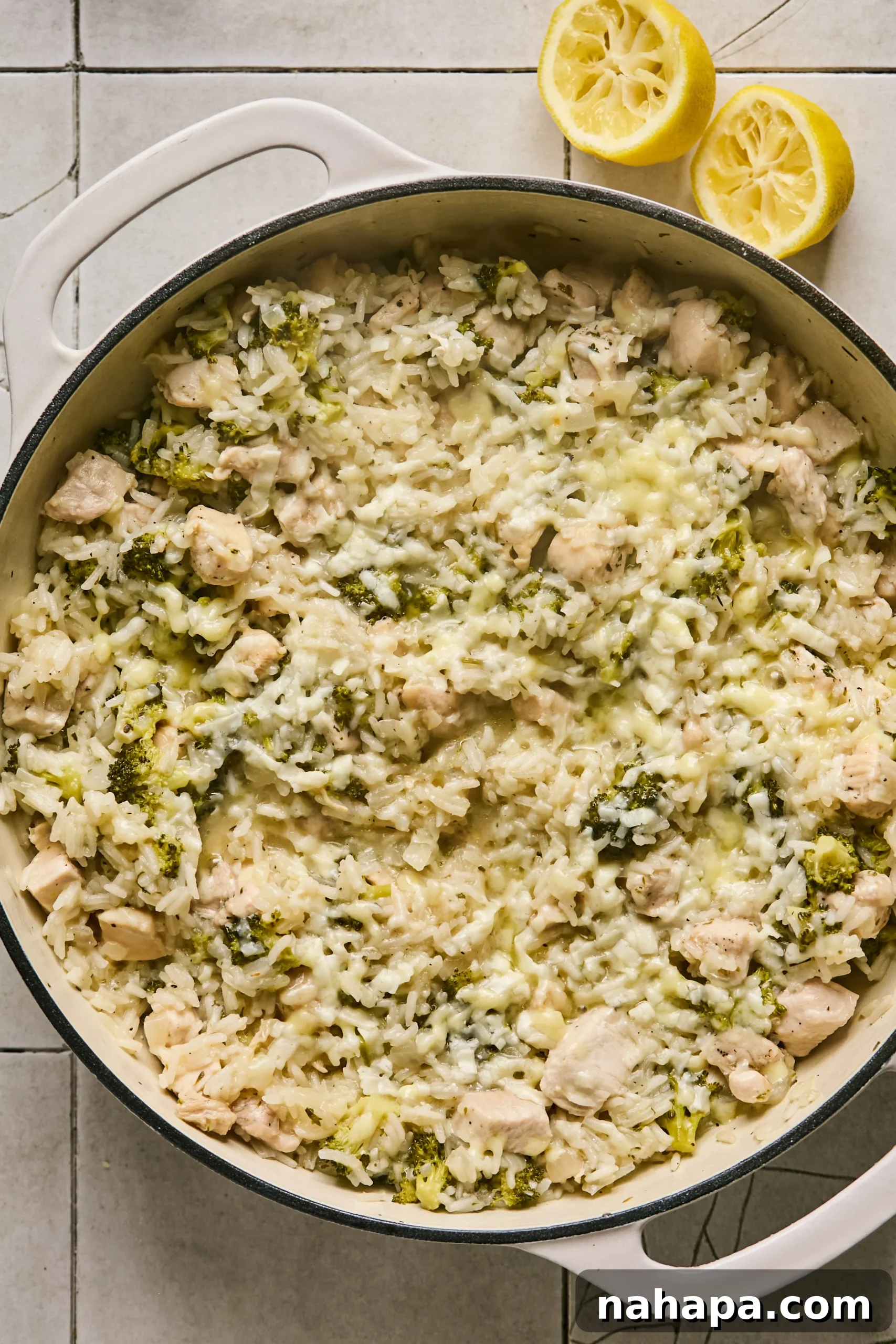 Finished one-pot broccoli cheddar chicken and rice, topped with melted cheese and fresh parsley, ready to serve.