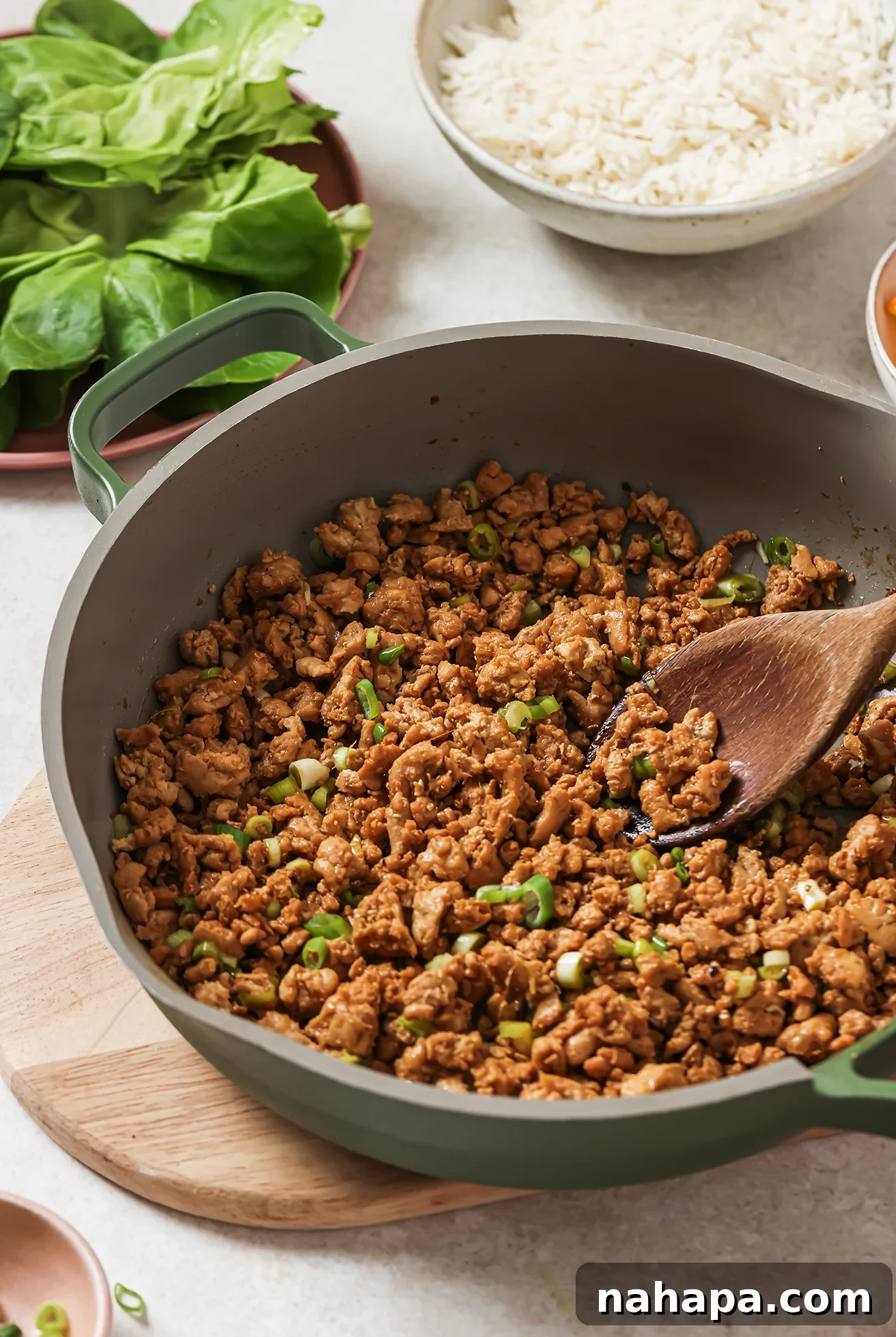 A pan filled with savory orange ground chicken, perfectly cooked and coated in sauce, ready to be scooped into lettuce cups.