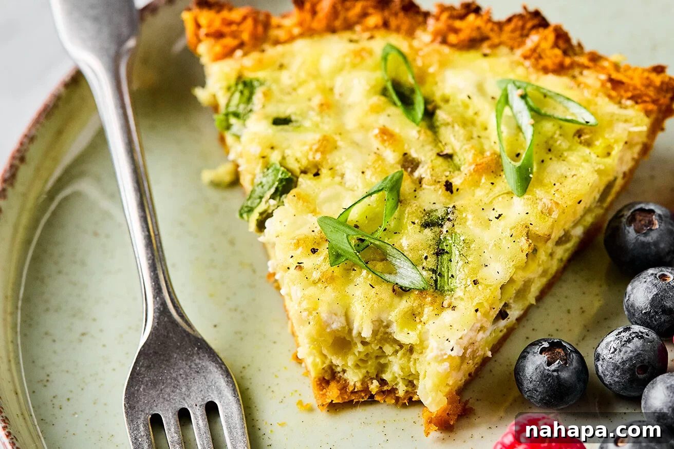 A slice of sweet potato quiche with a bite taken out of it and berries on the side.