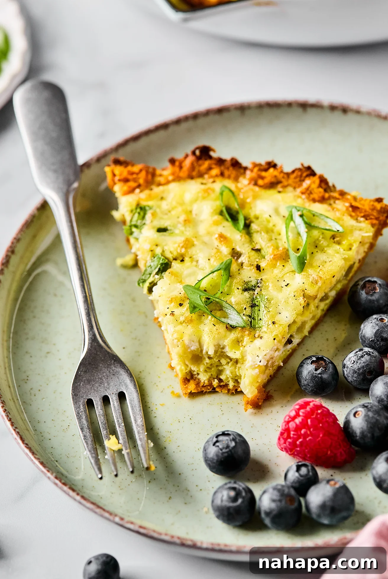 A slice of sweet potato quiche with a bite taken out of it and a fork.