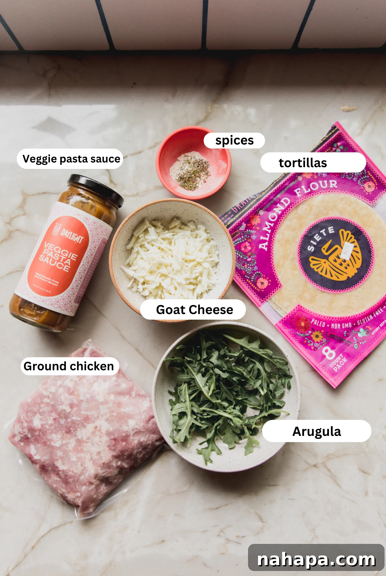 Individual ingredients for chicken parm tacos laid out in separate bowls, including ground chicken, sauce, cheese, and spices.