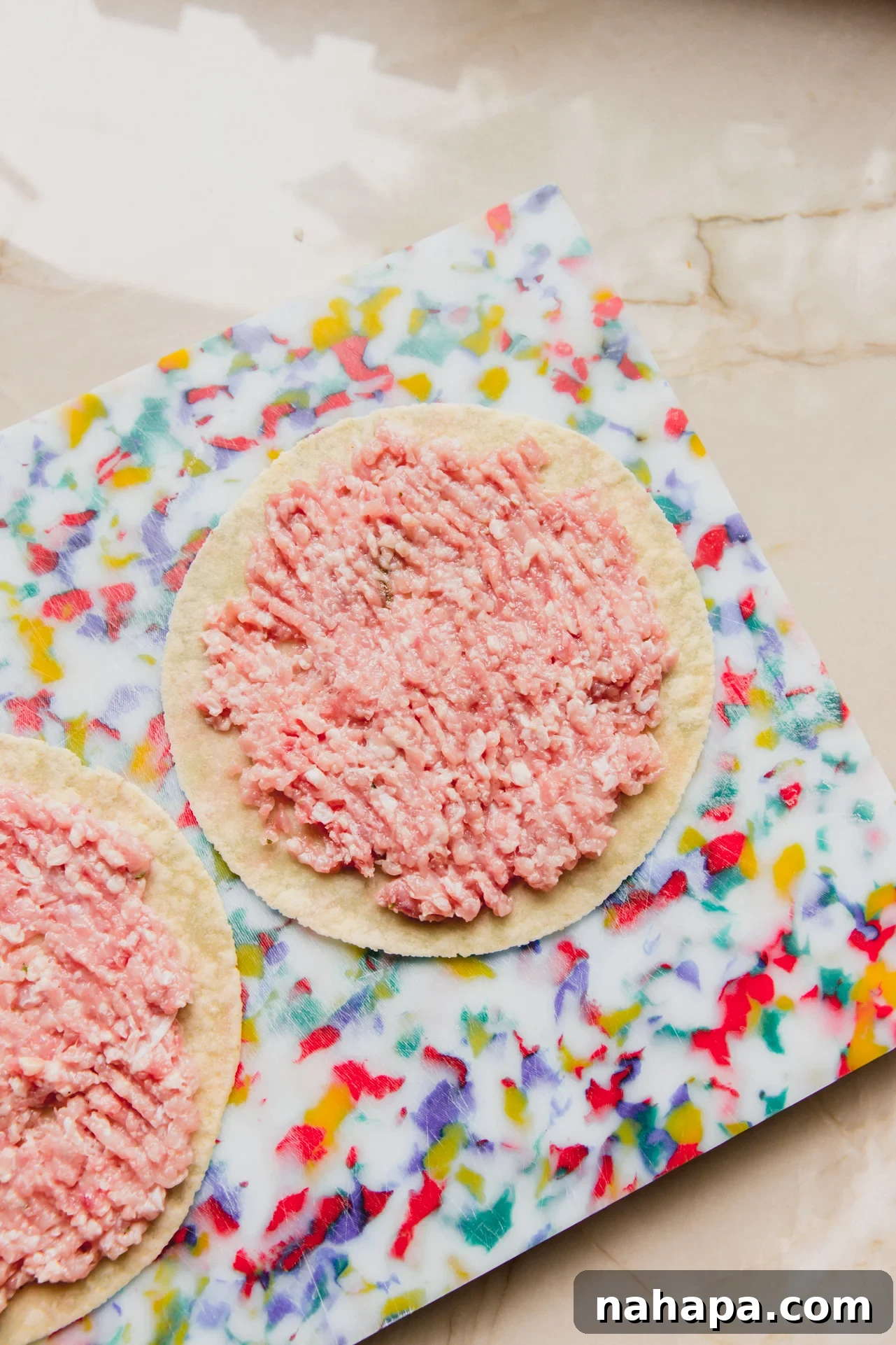 Two tortillas with a thin, even layer of chicken parm mixture spread across their centers.