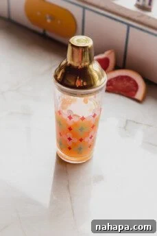 Paloma mocktail ingredients in a cocktail shaker, ready for vigorous mixing.