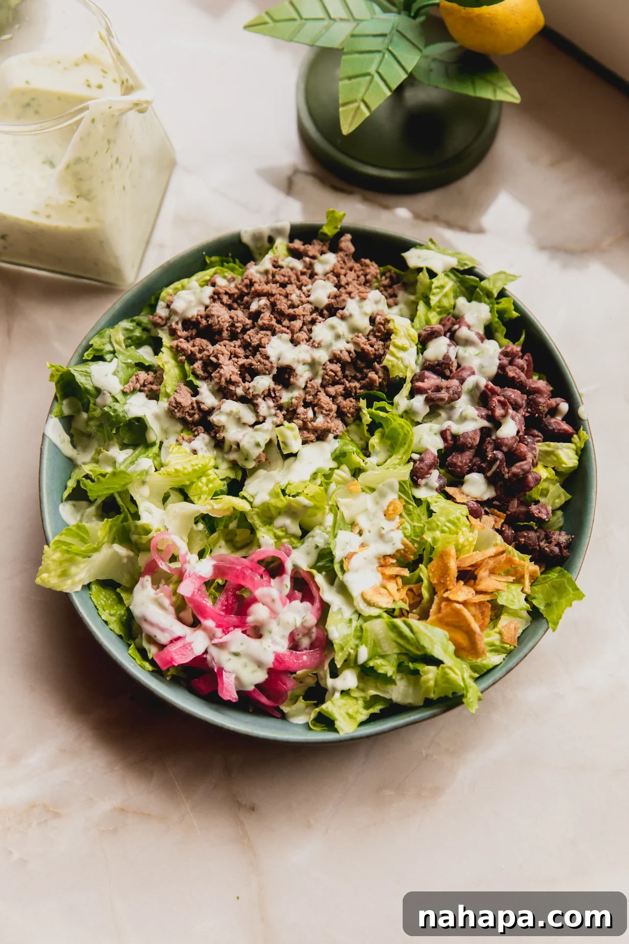 A beautifully assembled taco salad, generously topped with homemade taco salad dressing, showcasing a vibrant mix of fresh ingredients, protein, and crunchy elements.