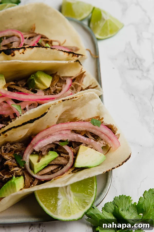 A bowl of slow cooker carnitas with a spoon, ready to be served