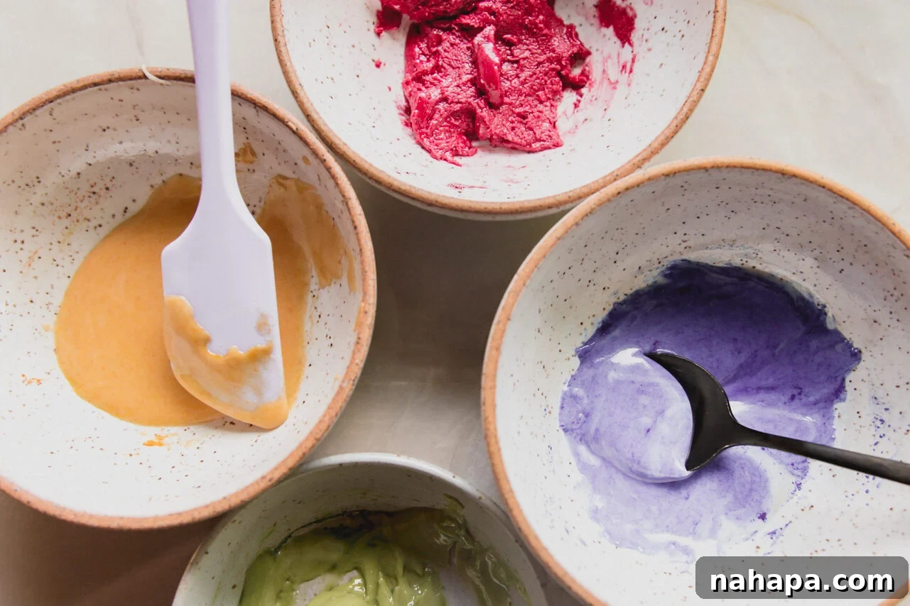 Four small bowls, each holding a portion of icing dyed with different natural food colorings.