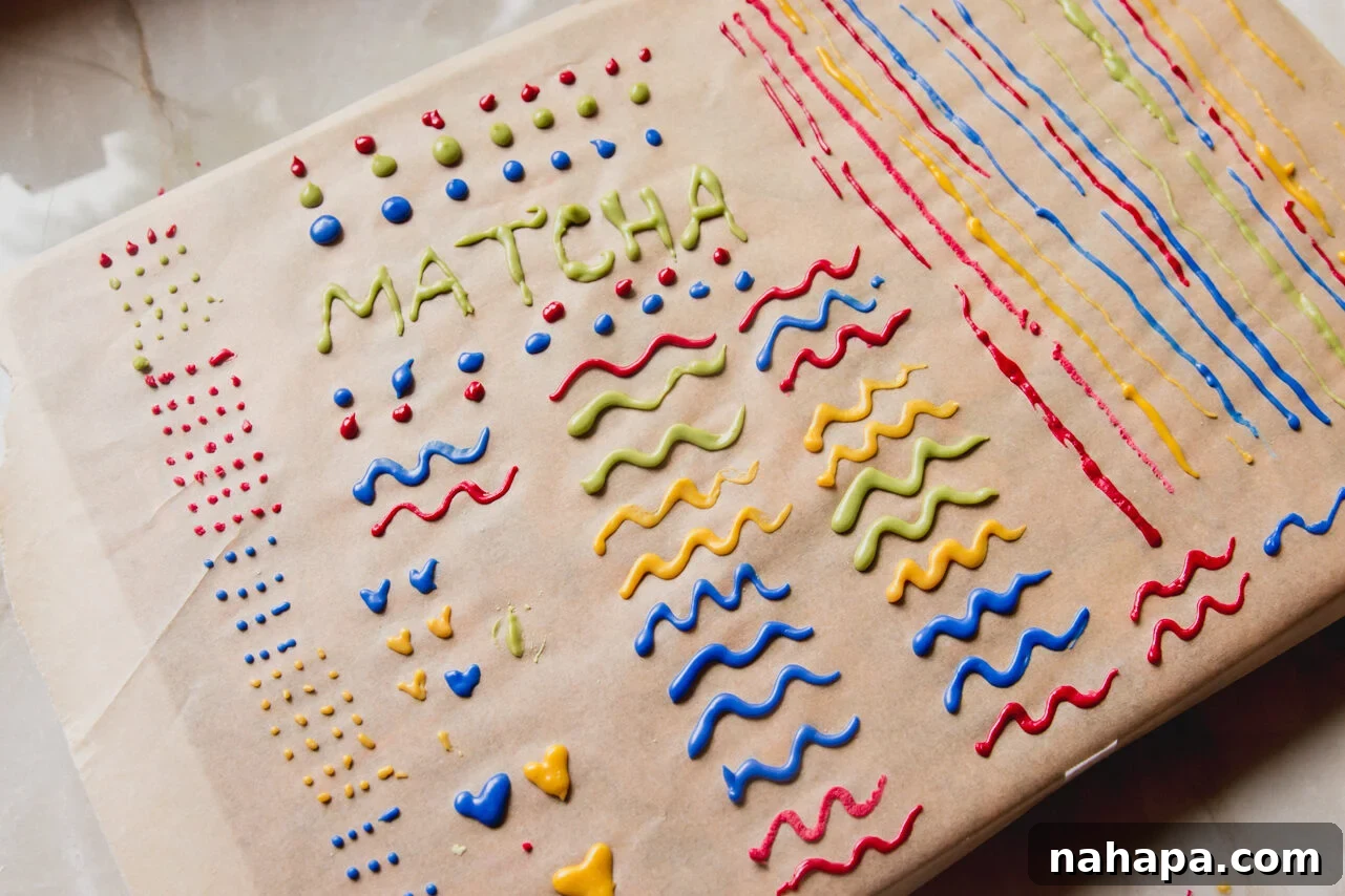 A sheet of parchment paper covered with piped lines of colored icing, drying at room temperature.