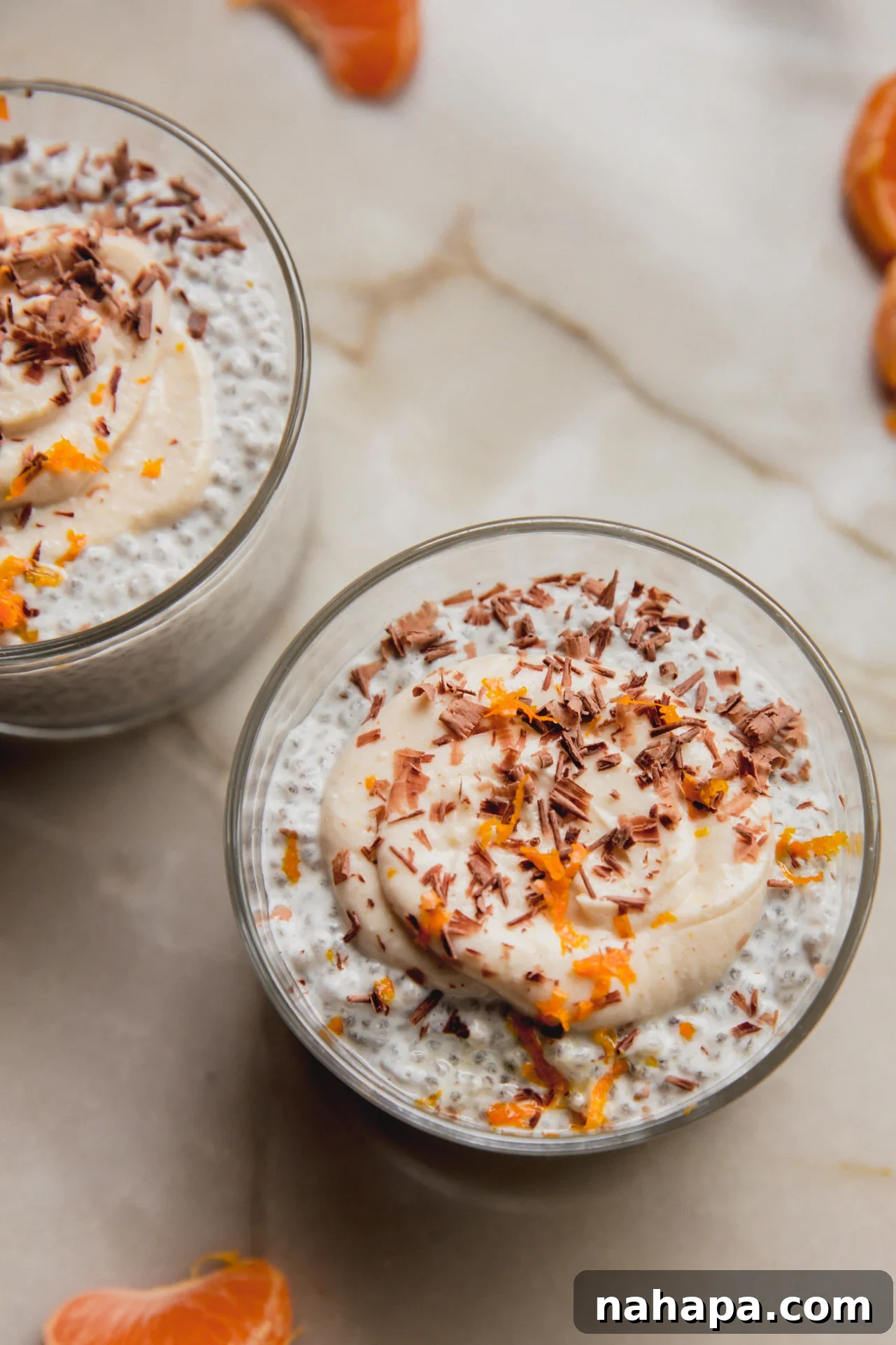Two cups of cannoli chia seed pudding on a counter, garnished with chocolate and zest.