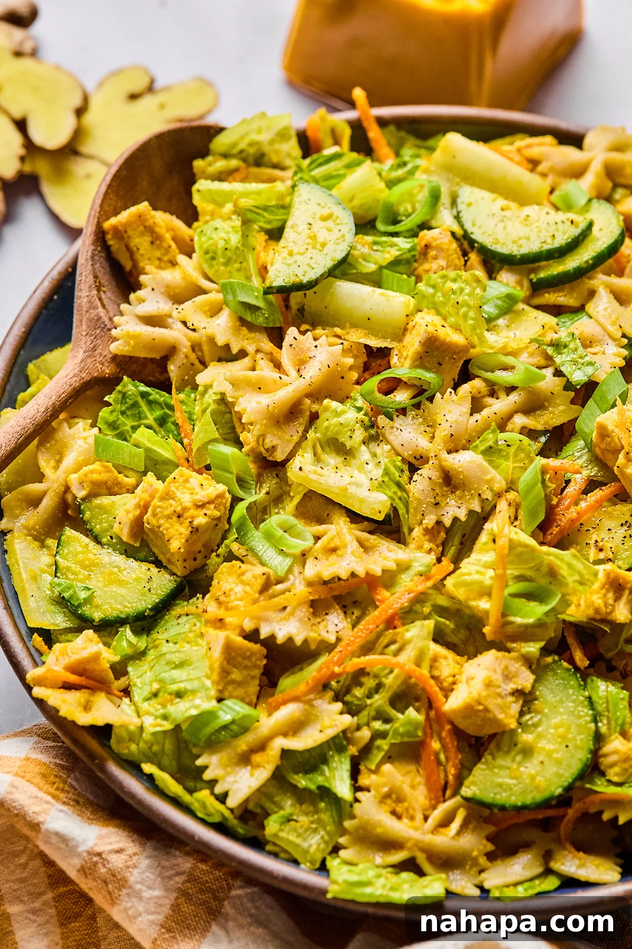 A large bowl of Japanese Ginger Dressing Pasta Salad with a salad spoon, highlighting its vibrant ingredients.