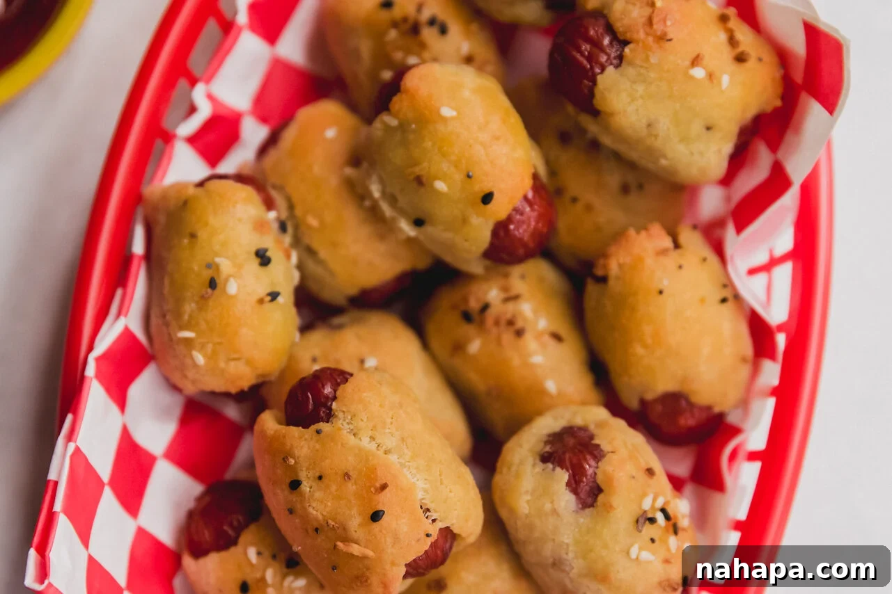 Cooked gluten-free pigs in a blanket in a serving basket, golden brown and ready to eat.