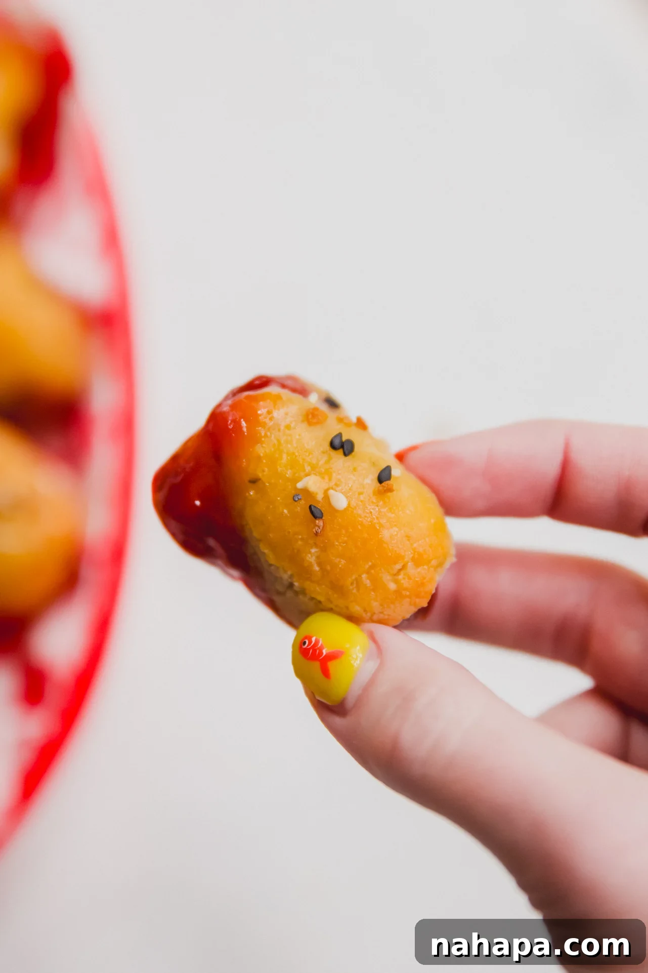 A gluten-free pig in a blanket dipped in ketchup, ready to be eaten.