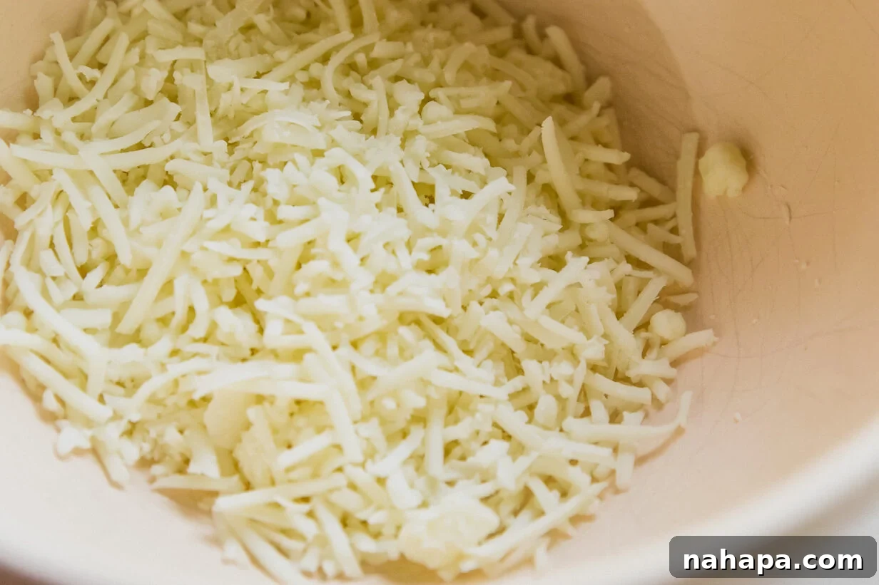 Shredded cheese and cream cheese in a bowl, ready to be combined.