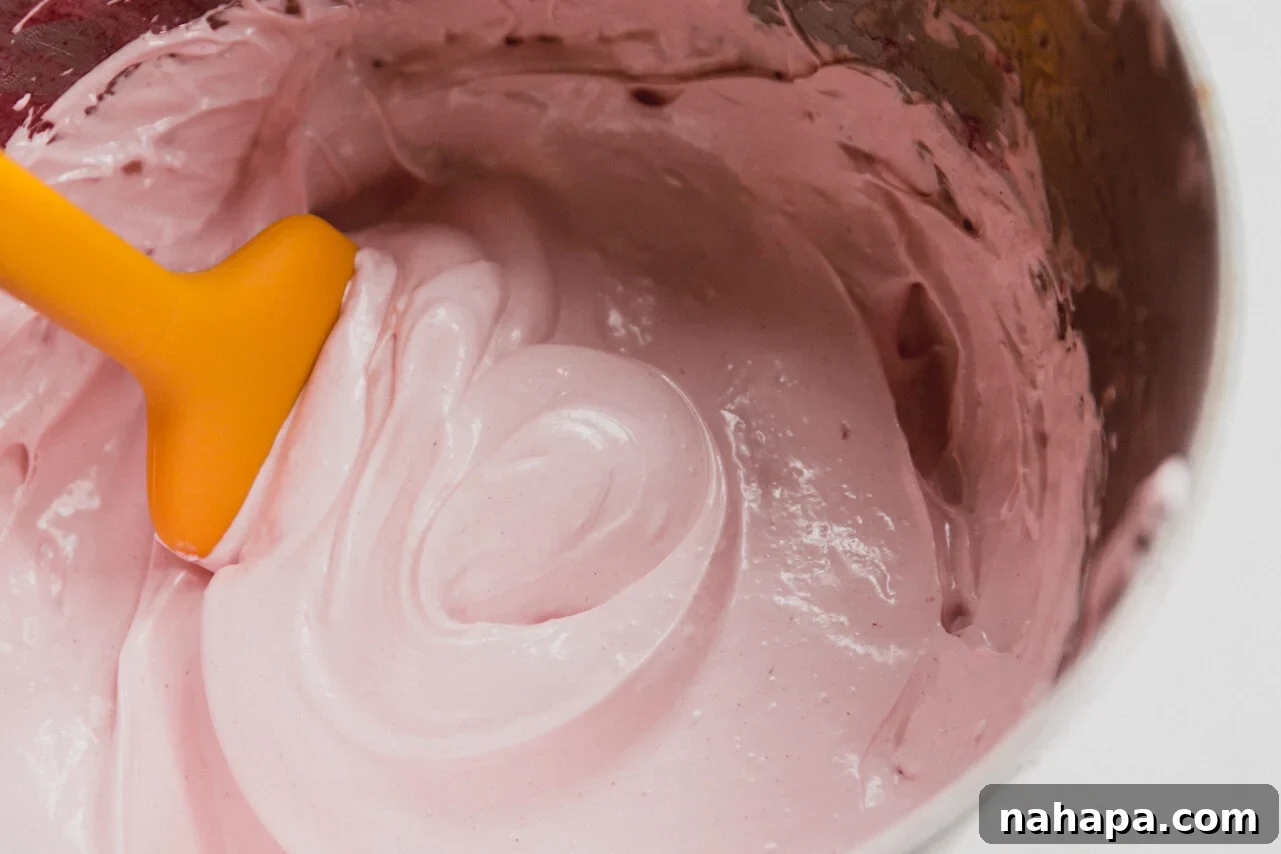 Blushing Berry Mallow Fluff 7 The fluffy, light pink strawberry marshmallow fluff after being whipped to perfection, showing its thick and airy consistency in the stand mixer bowl.