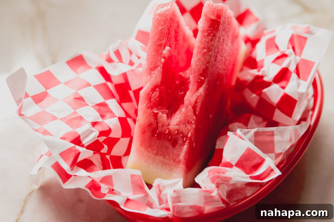 Watermelon Dream Swirl 6 A hollowed-out watermelon slice, prepared and sitting in a basket with checkered paper, ready to be filled with the Watermelon Dole Whip.