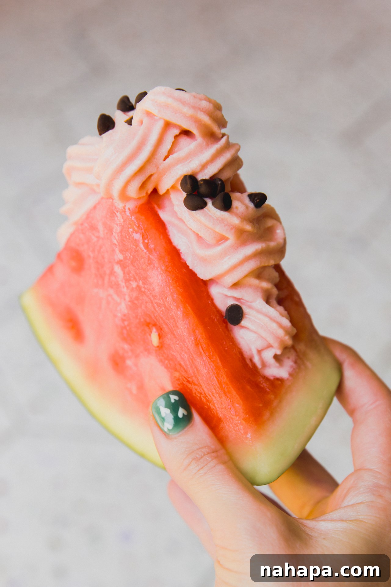 Watermelon Dream Swirl 7 A close-up shot of Watermelon Dole Whip swirled into a fresh watermelon slice, garnished with mini chocolate chips, highlighting the refreshing and vibrant nature of the dessert.