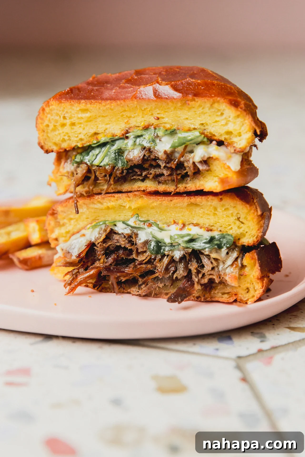 Pot roast sandwich sliced in half and stacked.