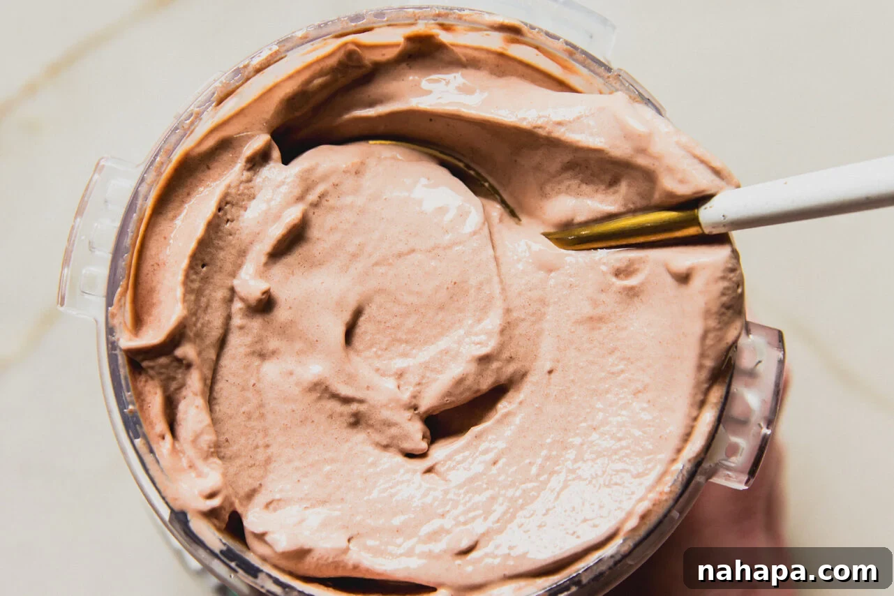 Chocolate protein ice cream fully prepared in a ninja creami container with spoon. 