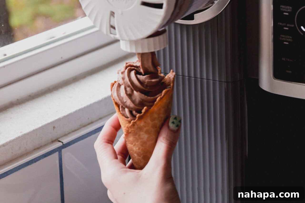 The ninja creami swirl attachment putting the chocolate protein ice cream into a cone.