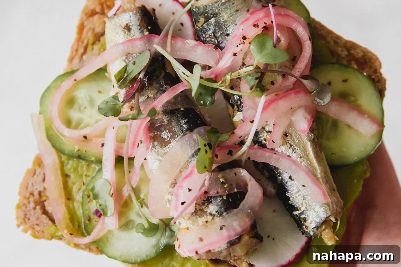 A piece of sardine toast with pickled onions and salt on top.