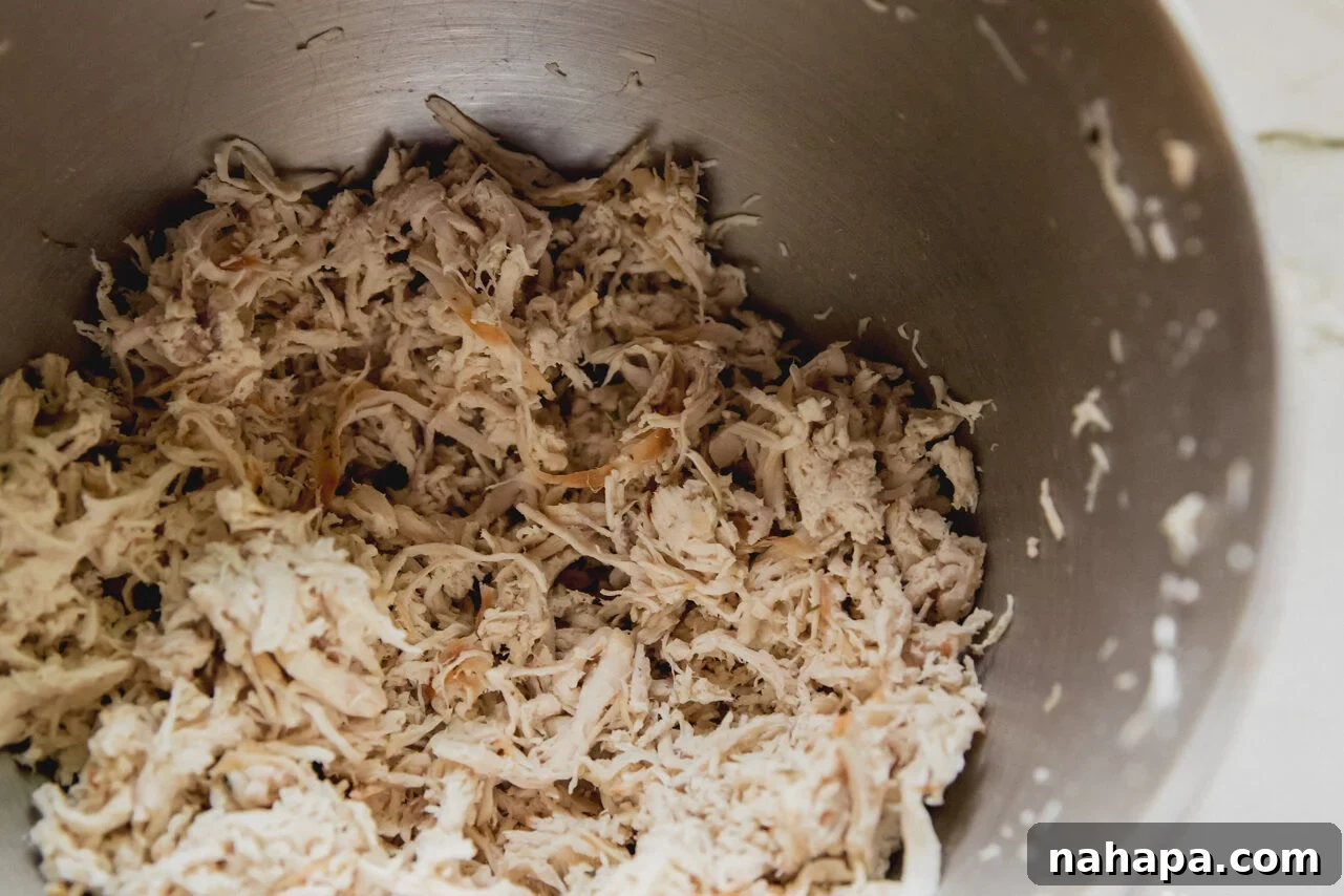 A bowl filled with finely shredded and chopped chicken, ready for mixing.