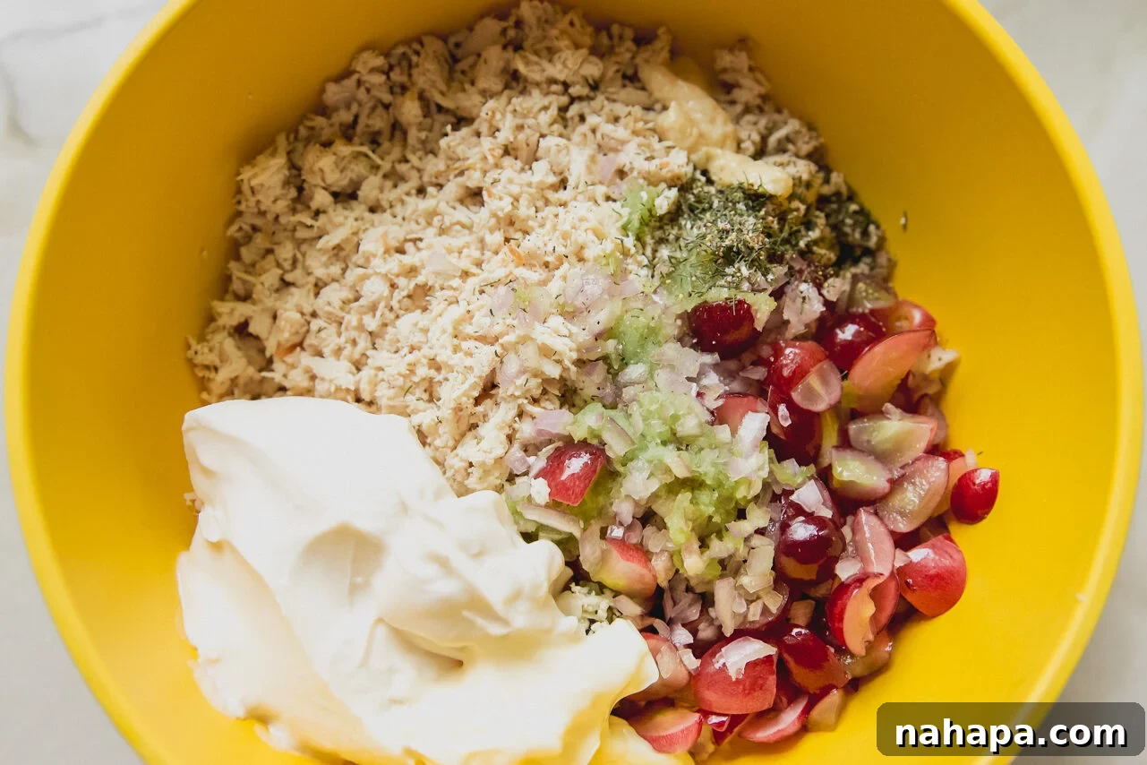All the chicken salad ingredients gathered in a bowl before being thoroughly mixed together.