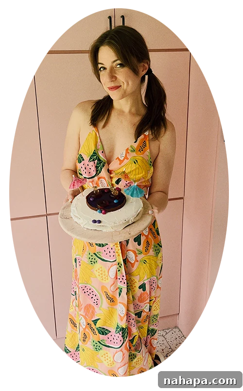 Food blogger, Michelle Hoover in a pink kitchen holding a swimming pool cake on a plate, smiling proudly.