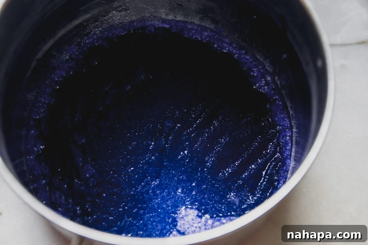 Apple juice, gelatin, and blue spirulina combined in a pot on the stove, beginning to heat to create the jello pool.