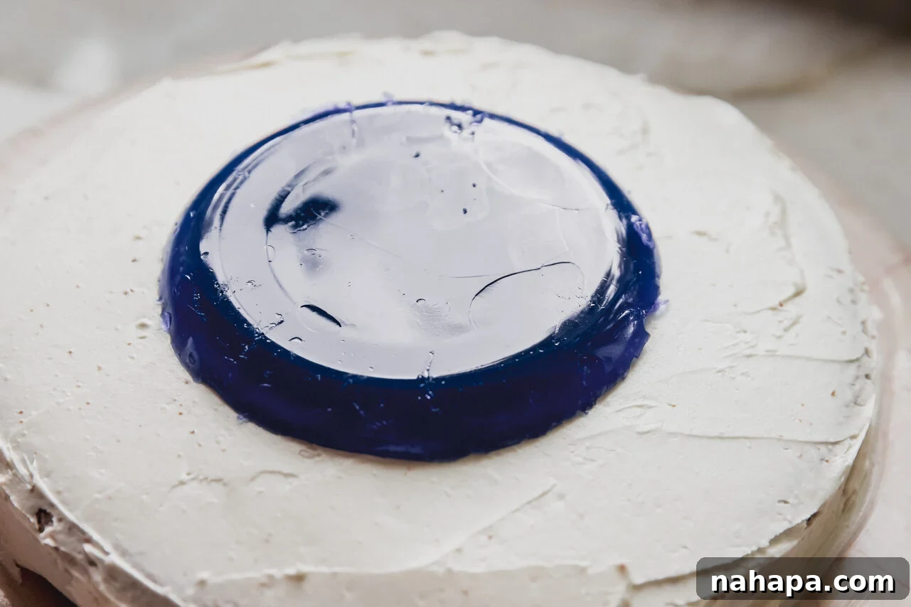 A vibrant blue jello pool carefully placed on top of a prepared and frosted cake, ready for decoration.