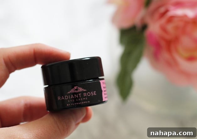 A hand holding a small container of radiant rose .