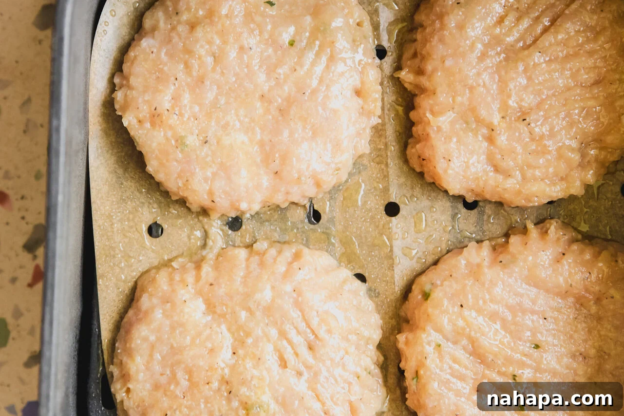 Raw chicken patties arranged in an air fryer basket, ready to be cooked.