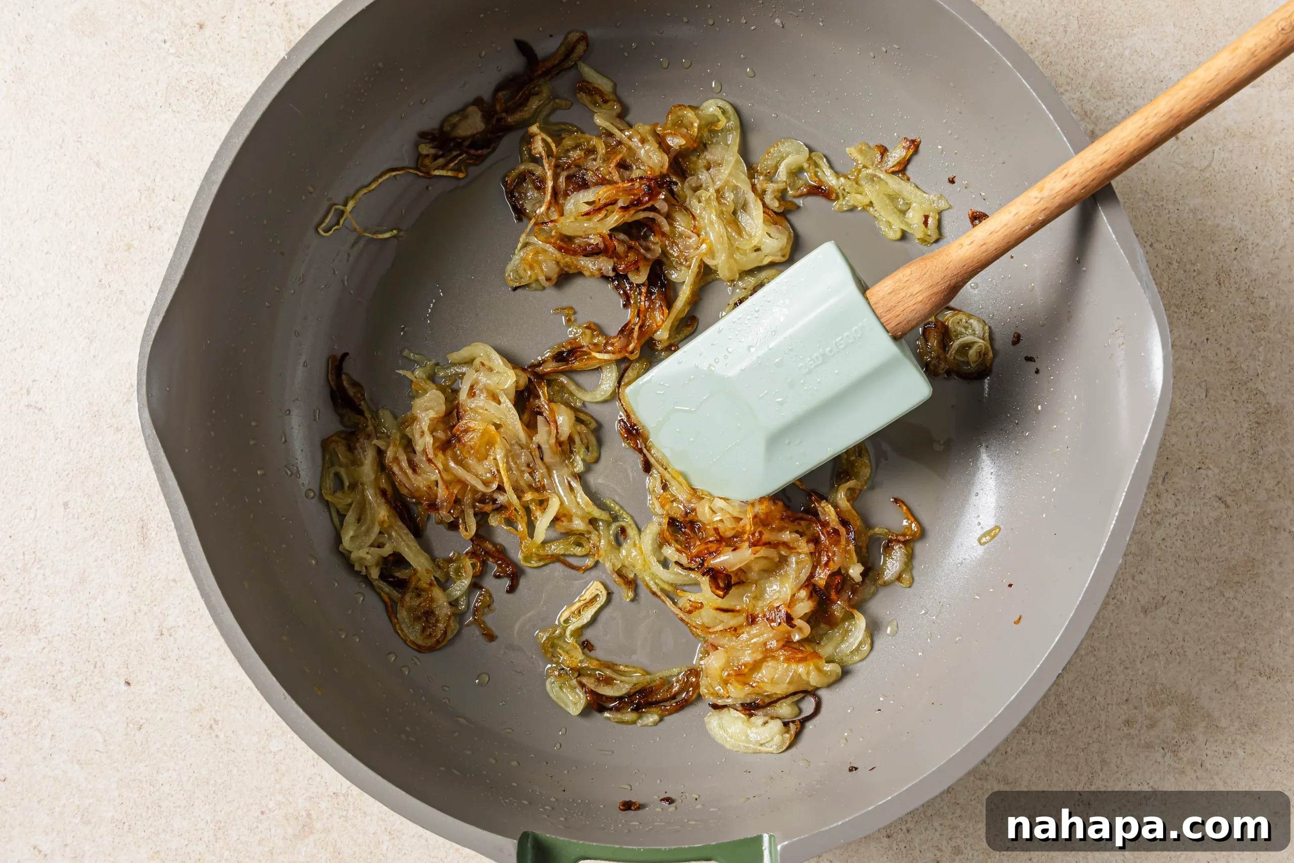 Thinly sliced yellow onions caramelizing slowly in a pan with ghee.