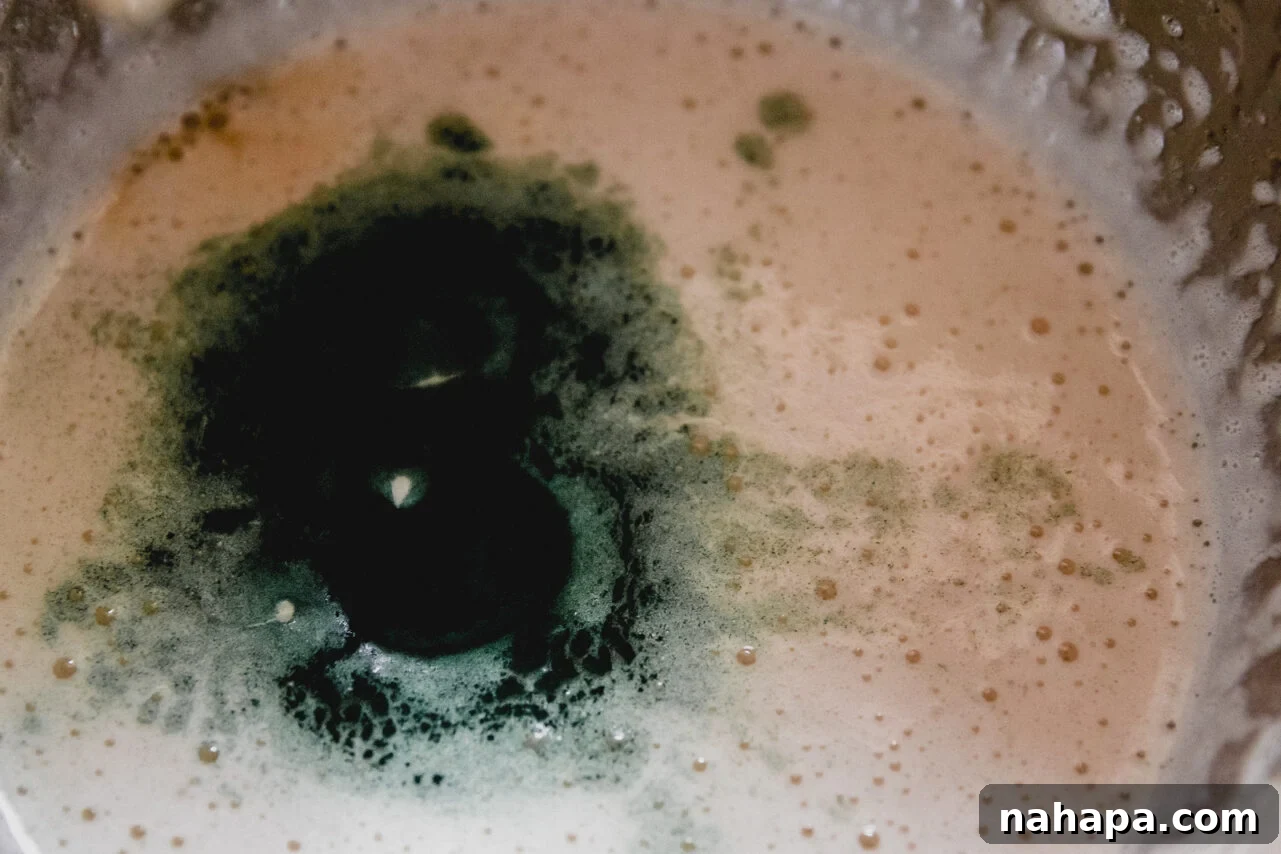 Watermelon Cloud Treats 4 A green marshmallow mixture being prepared in a metal mixing bowl with an electric mixer.