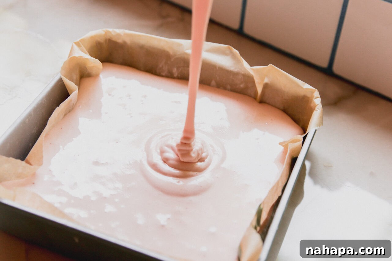 Watermelon Cloud Treats 7 The freshly mixed pink marshmallow layer being poured smoothly over the set green layer in the baking pan.
