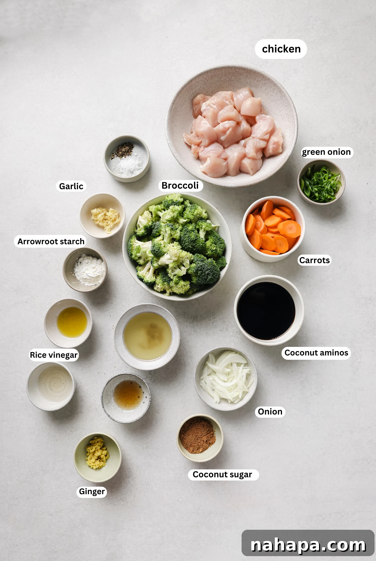 A flat lay of various ingredients for slow cooker chicken and broccoli laid out in separate bowls, including chicken, broccoli, carrots, onions, and sauce components.