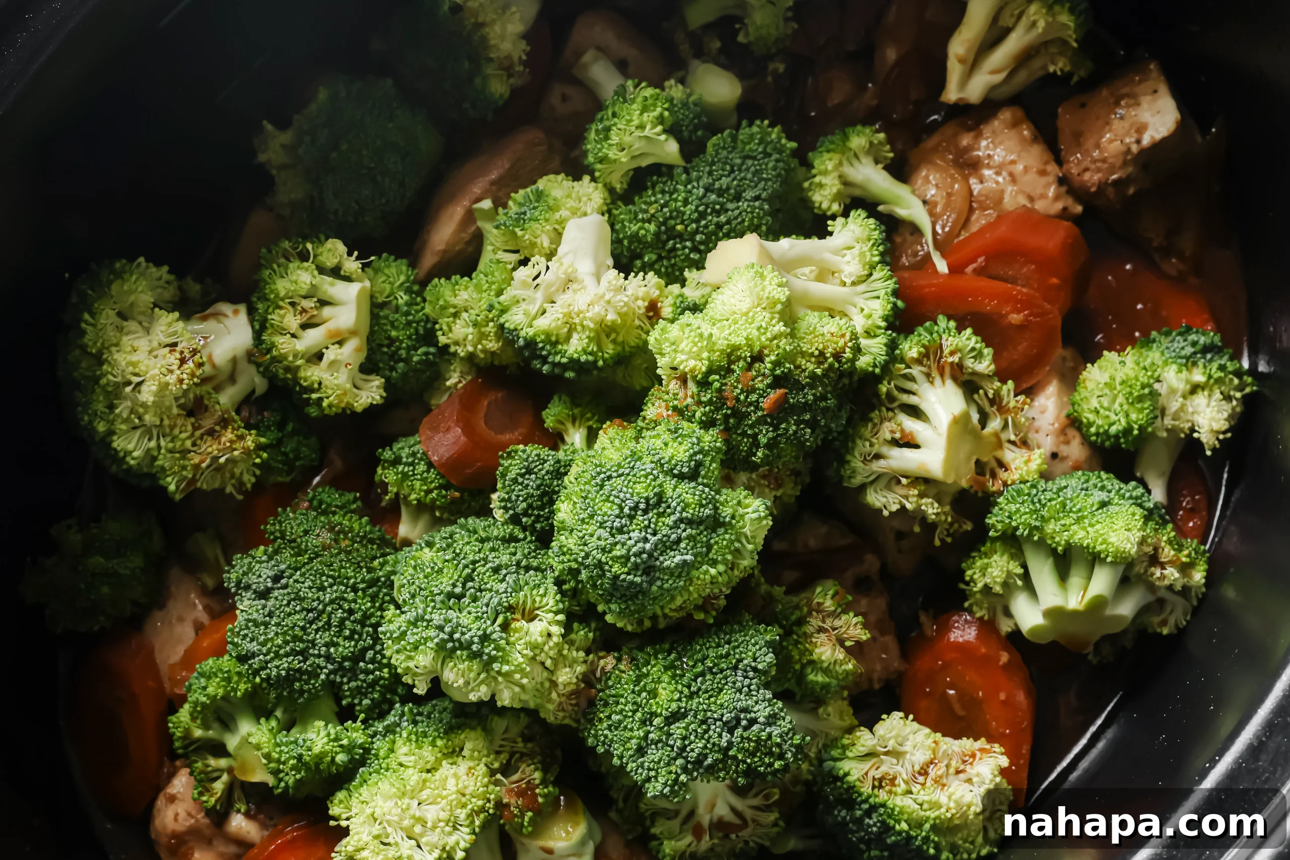 Cooked chicken and carrots in the slow cooker with fresh broccoli florets added on top.