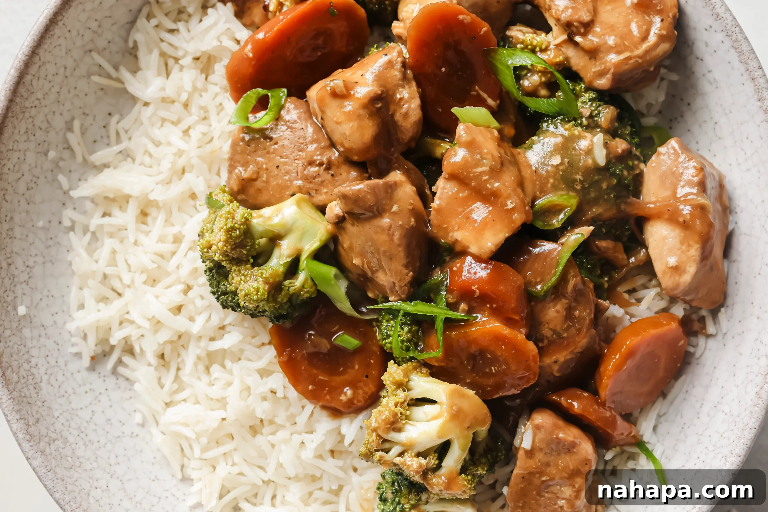 A serving of slow cooker chicken and broccoli alongside white rice, topped with fresh chopped green onions.