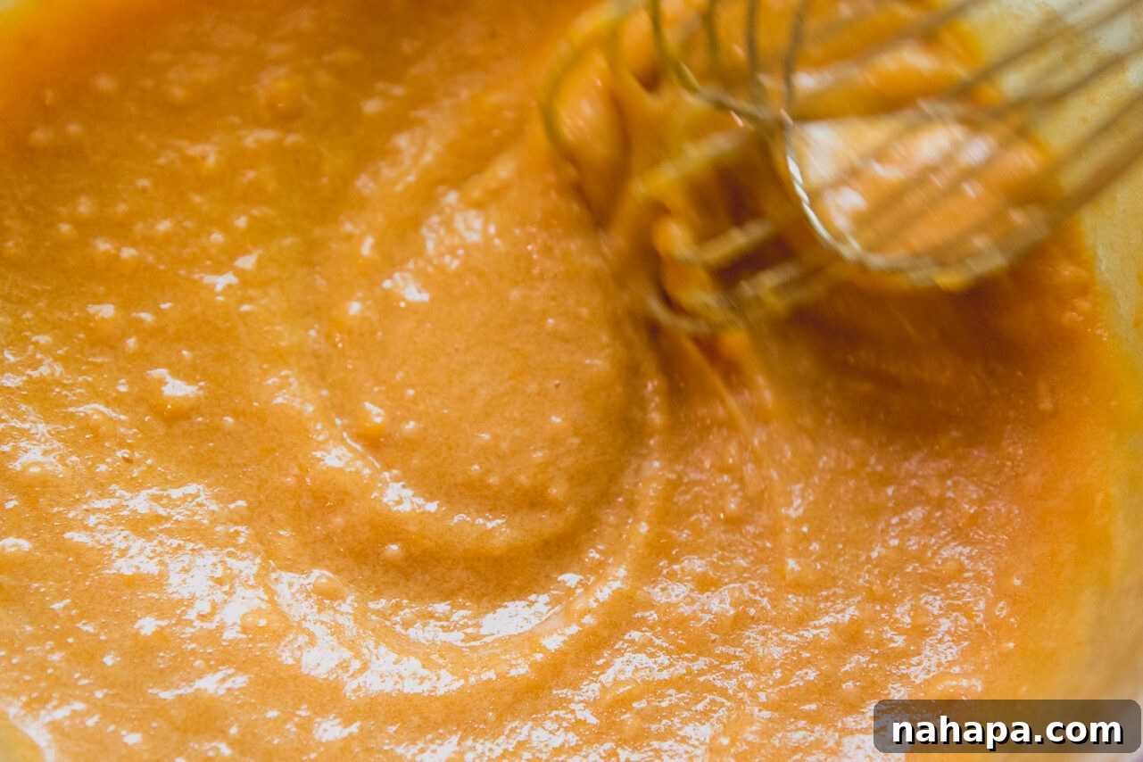 Peachy Protein Rings 6 Thickened peach protein ring mixture being whisked in a pot on the stove, showing dissolution of ingredients.