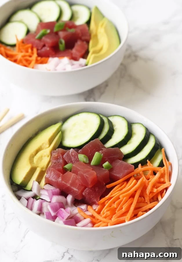 A beautifully presented bowl brimming with fresh tuna poké, crisp vegetables, and creamy avocado, making for a healthy and satisfying meal.